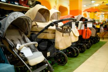 Row of baby strollers in children's store. Showcase with perambulator variety in kid's shop, child transportation department, nobody