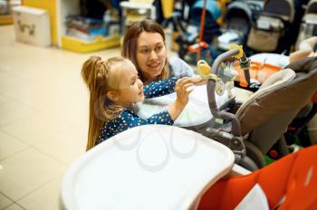 Mother and little daughter buying baby stroller in store. Mom and adorable girl near the showcase in children's shop, happy childhood, family makes a purchase in kid's market