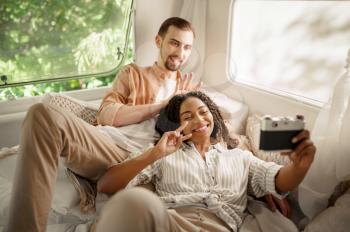 Love couple makes selfie in rv bed, camping in a trailer. Man and woman travels on van, romantic vacations on motorhome, campers leisures in camping-car