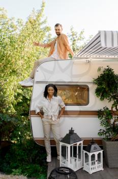 Happy love couple poses near rv, camping in a trailer. Man and woman travels on van, romantic vacations on motorhome, campers leisures in camping-car
