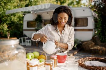Female person cooking breakfast near the rv, trailer camping. Couple travels on van, romantic vacations on motorhome, camper leisures in camping-car, camp