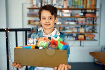 Little boy holds box of different puzzle cubes. Toy for brain and logical mind training, creative game, solving of complex problems