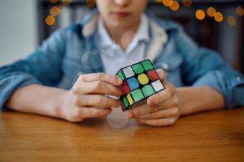 Little boy trying to solve puzzle cube, selective focus on hands. Toy for brain and logical mind training, creative game, solving of complex problems