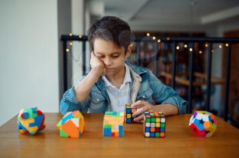 Little boy looks on puzzle cubes. Toy for brain and logical mind training, creative game