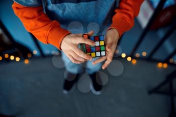Male kid holds puzzle cube, selective focus on hand. Toy for brain and logical mind training, creative game, solving of complex problems