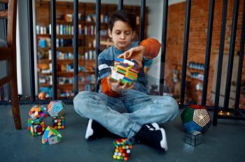 Child trying to solve difficult puzzle cubes. Toy for brain and logical mind training, creative game, solving of complex problems