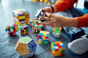 Male child trying to solve different puzzle cubes. Toy for brain and logical mind training, creative game, solving of complex problems