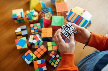 Little boy holds puzzle cube with numbers. Toy for brain and logical mind training, creative game, solving of complex problems