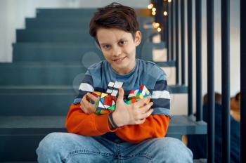 Cheerful little boy play with puzzle cubes. Toy for brain and logical mind training, creative game, solving of complex problems