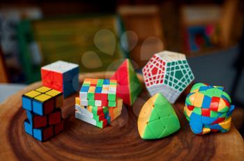 Different colorful puzzle cubes with unusual shape on wooden stump, closeup view, nobody. Toy for brain and logical mind training, creative game, solving of complex problems