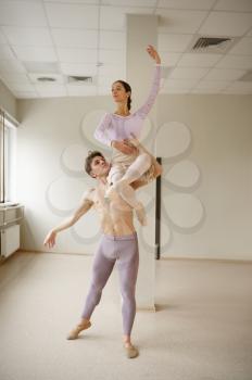 Couple of ballet dancers, dancing in action. Ballerina with partner training in class, dance studio interior
