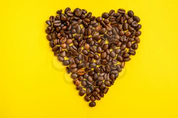 Coffee bean heart isolated on yellow background, top view. Organic vegetarian food, grocery assortment, natural eco products, healthy lifestyle concept