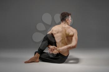 Yoga doing stretching exercise in studio, grey background. Strong man practicing yogi , asana training, top concentration, healthy lifestyle