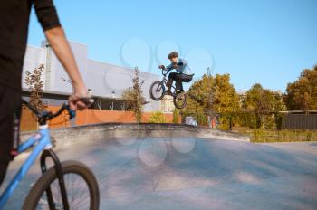 Bmx rider on ramp, jump on ramp in action, training in skatepark. Extreme bicycle sport, dangerous cycle exercise, street riding, teens biking in summer park