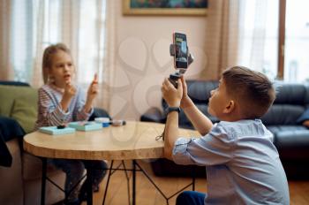 Two children bloggers records blog on camera, little vloggers. Kids blogging in home studio, social media for young audience, online internet broadcast