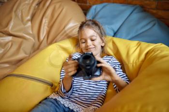 Happy little girl with camera, child blogger. Kid blogging in home studio, social media for young audience, online internet broadcast, creative hobby