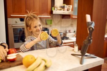 Happy little girl makes food blog, child blogger. Kid blogging in home studio, social media for young audience, online internet broadcast, creative hobby