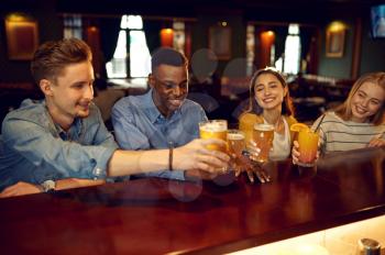 Cheerful friends drinks beer at the counter in bar. Group of people relax in pub, night lifestyle, friendship, event celebration