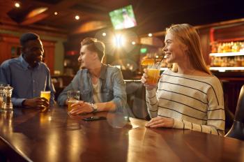 Three friends with alcohol beverages having fun at the table in bar. Group of people relax in pub, night lifestyle, friendship, event celebration