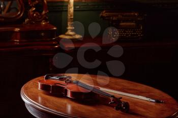 Violin in retro style on wooden table, closeup view, nobody. Classical string musical instrument, music art, old viola, dark background
