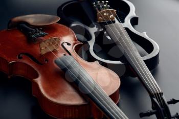 Wooden retro violin and modern electric viola, closeup view, nobody. Two classical string musical instruments, black background