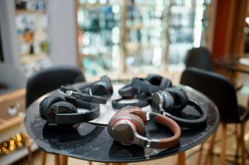 Different headphones on the counter in speaker system store, nobody. Audio shop choice, showcase with earphones, multimedia salon assortment