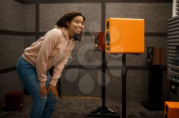 Woman choosing acoustics in speaker system store. Female person in audio shop, amplifier on background, buyer in multimedia salon