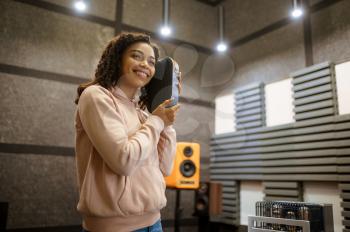 Smiling woman holds sound speaker in music store. Female person in audio shop, amplifier on background, buyer in multimedia salon