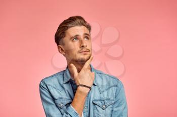 Pensive man portrait, pink background, emotion. Face expression, male person looking on camera in studio, emotional concept, feelings