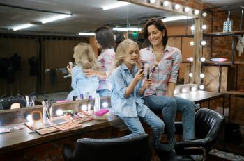Mother and daughter leisures in makeup salon. Mom and little girl play stylists together, happy childhood, glamour family
