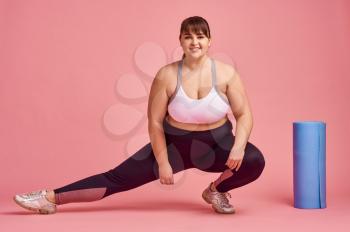 Overweight woman doing fitness exercise, body positive, pink background. Obesity fighting, striving for a healthy lifestyle