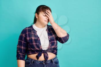 Frustrated overweight woman, blue background. Obesity fighting, sad female person without complexes, striving for a healthy lifestyle, loss weight problem