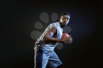 Basketball player, training with ball in studio, black background. Professional male baller in sportswear playing sport game, tall sportsman