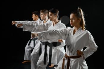 Four karate fighters poses in white kimono, group training, dark smoky background. Karatekas on workout, martial arts, fighting competition