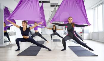 Fly yoga, female group training with hammocks. Fitness, pilates and dance exercises mix. Women on yogi workout in sports studio