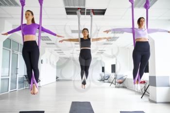 Fly anti-gravity yoga, female group training with hammocks. Fitness, pilates and dance exercises mix. Women on yoga workout in sports studio