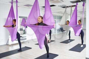 Aerial antigravity yoga, group training with hammocks. Fitness, pilates and dance exercises mix. Women on yogi workout in sports studio