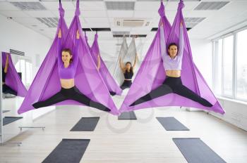 Fly yoga, female group training, hanging on hammocks. Fitness, pilates and dance exercises mix. Women on yogi workout in sports studio