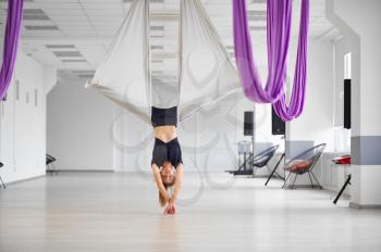 Aerial yoga, woman hanging upside down on hammock. Fitness, pilates and dance exercises mix. Female person on yogi workout in sports studio