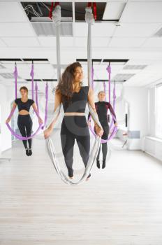 Fly yoga studio, female group training, hanging on hammocks, antigravity. Fitness, pilates and dance exercises mix. Women on yogi workout in gym