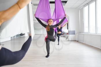 Aerial or antigravity yoga, group training, hanging on hammocks. Fitness, pilates and dance exercises mix. Women on yogi workout in gym, fit lifestyle