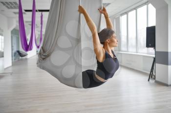 Aerial yoga, slim woman on hammock, stretching. Fitness, pilates and dance exercises mix. Female person on yogi workout in sports studio