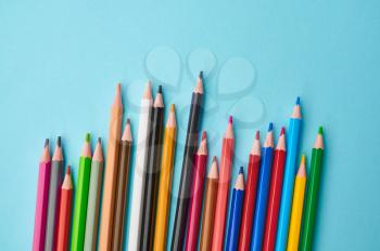 Set of colorful pencils closeup, blue background. Office stationery supplies, school or education accessories, writing and drawing tools