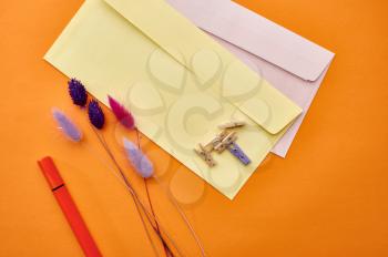 Postal envelopes and paper clips closeup, orange background. Office stationery supplies, school or education accessories, writing and drawing tools