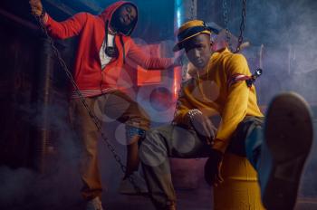 Two stylish rappers dancing in studio with cool underground decoration. Hip-hop performers, trendy rap singers, break-dancers