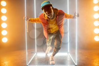 Stylish rapper on the stage with illuminated cube. Hip-hop performer, rap singer, break-dance performing, entertainment lifestyle