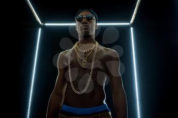 Serious rapper in gold chains, bottom view, dark background. Hip-hop performer, rap singer, break-dance performing, entertainment lifestyle, breakdancer