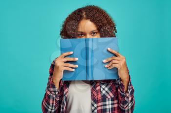 Pretty woman with book, blue background, positive emotion. Face expression, female person looking on camera in studio, emotional concept, feelings