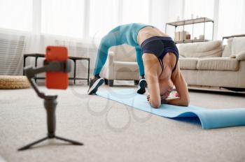 Slim girl doing stretching exercise at home, online fit training at the laptop. Female person in sportswear, internet sport workout, room interior on background