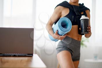Woman holds mat, online fitness training. Female person in sportswear, internet sport workout, room interior on background